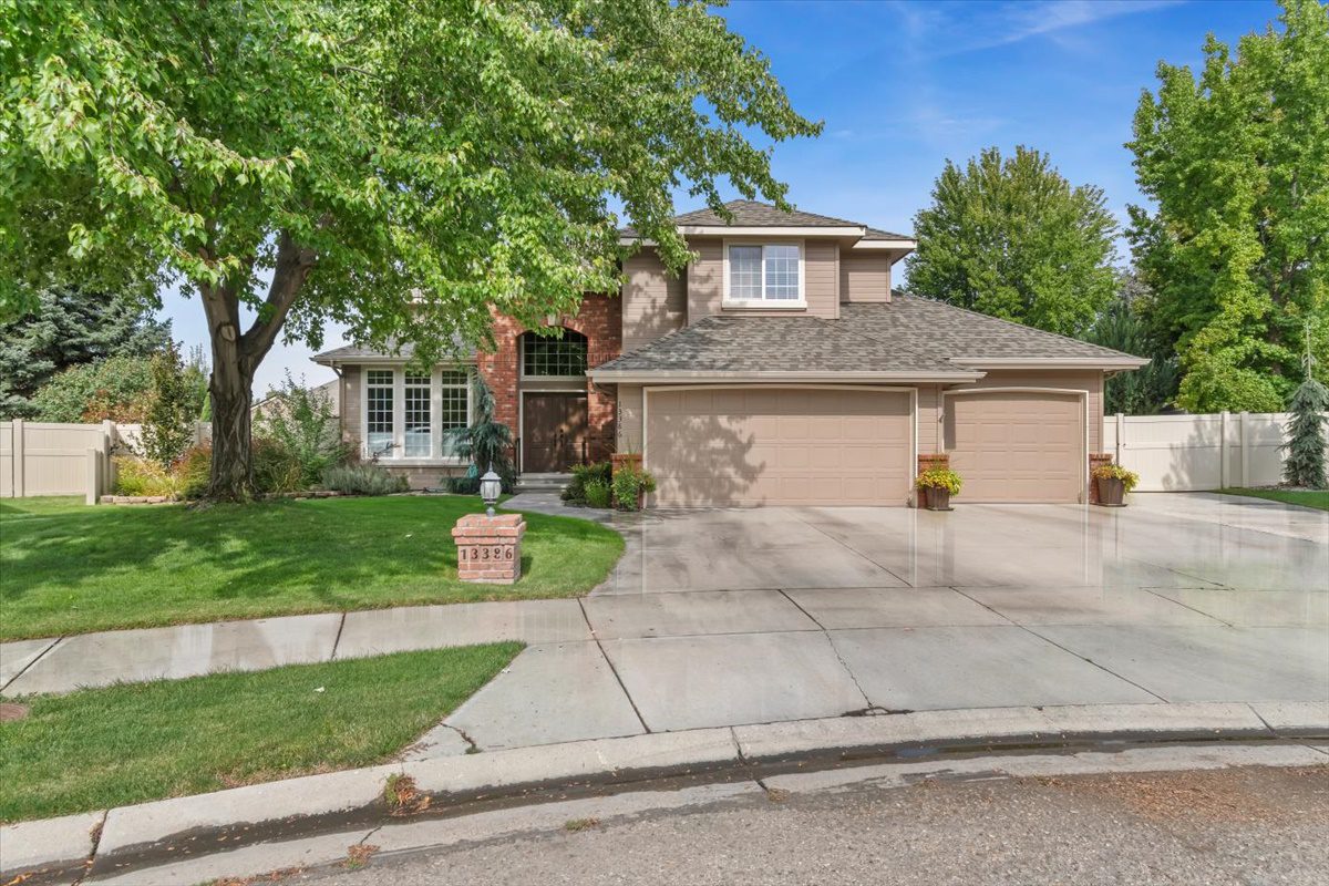 Two-story suburban home with a three-car garage and lush greenery.