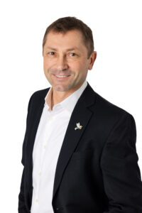 Professional man in a black blazer and white shirt smiling.