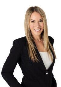 Confident woman in black blazer smiling at the camera.